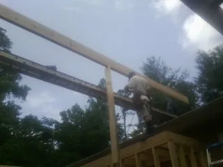 Carpenter setting a ridge beam over a new addition frame — Ice Dam Removal by Roofing Brothers in Langlois