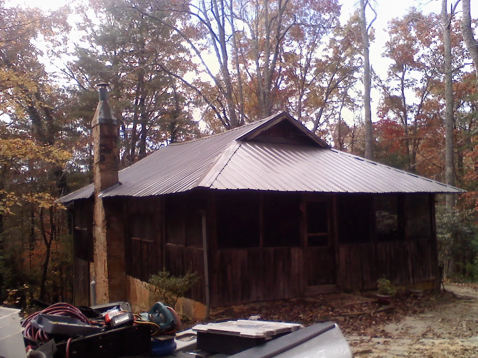 Brown metal hip roof on an old cabin with a stone chimney in Langlois