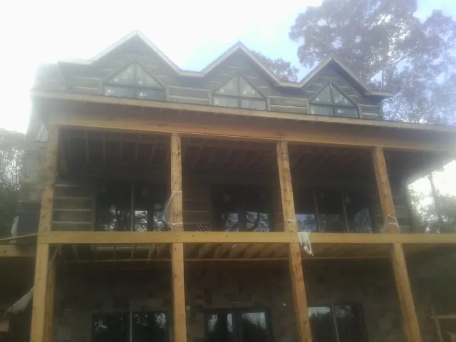 Dormers and porch framing on a large log home under construction — Roof Coating work by our crew in Langlois