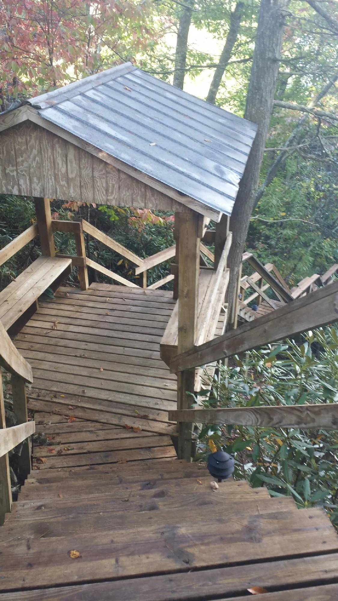 Metal roofed shelter over wooden steps on a wooded walkway — Skylight Repair & Installation work by our crew in Langlois
